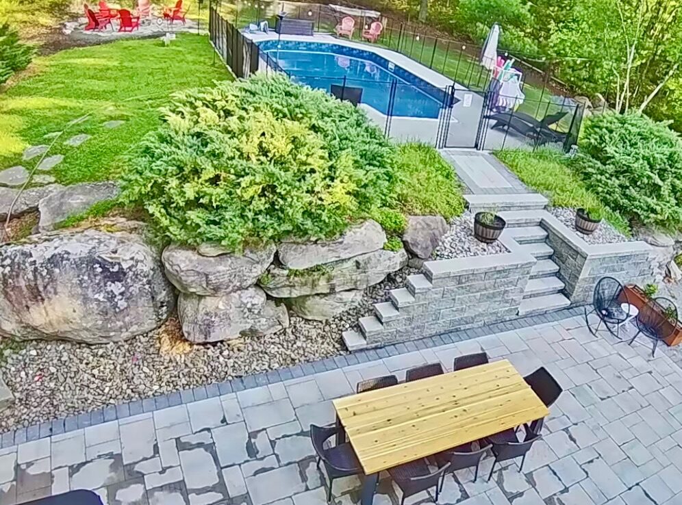 Stone patio with dining table and steps to pool